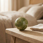 Jade stone massage ball on a bedside table with linen towel